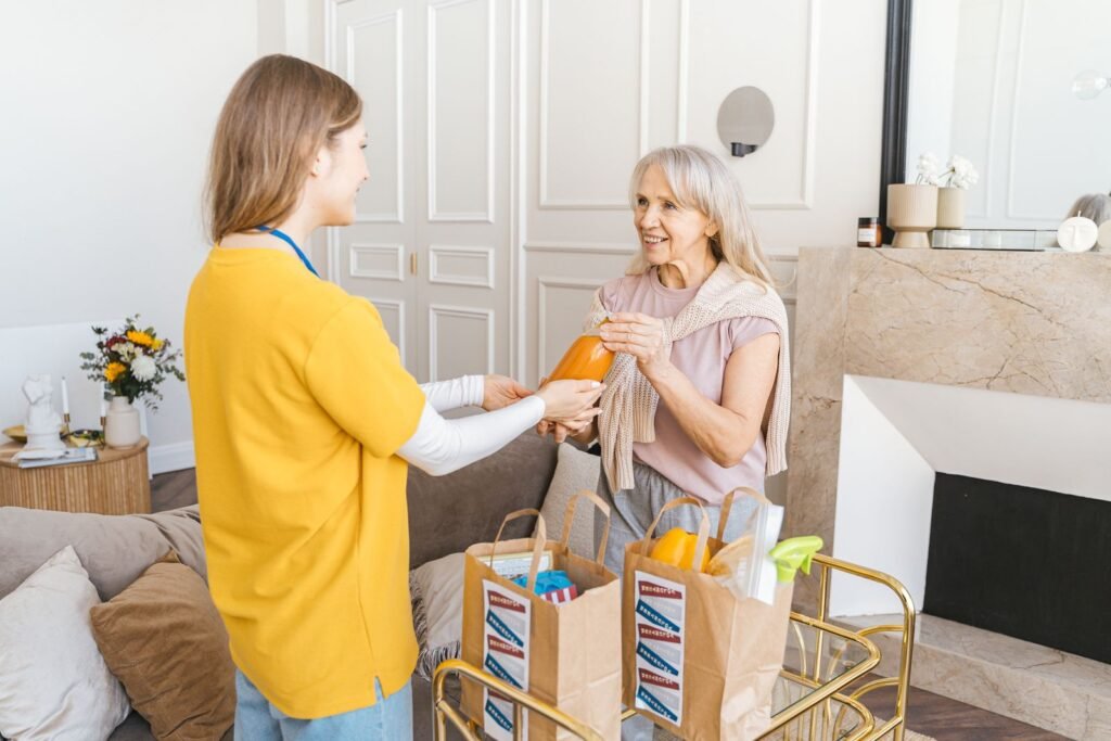 A caregiver helping an older woman unpack groceries at home