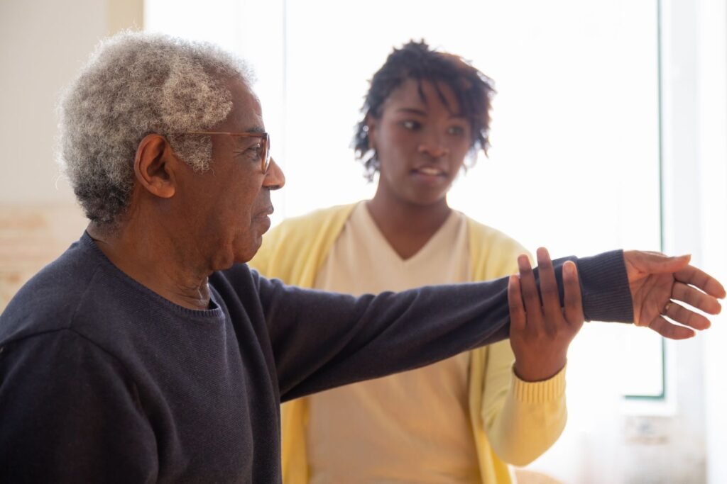 A caregiver helping an older man with gentle arm movement at home