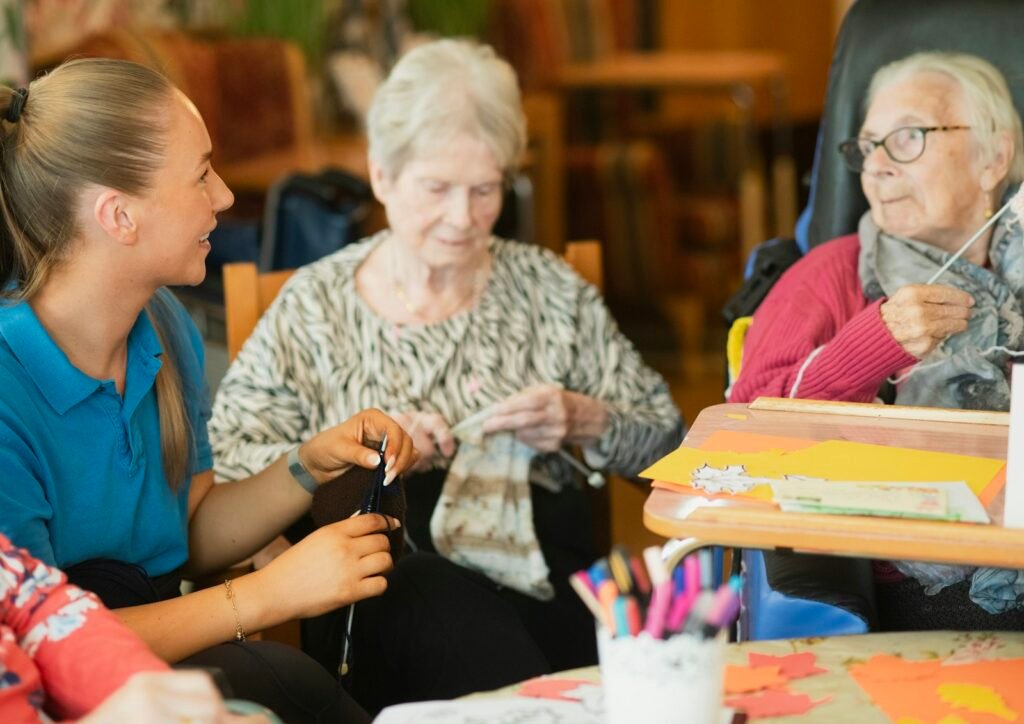 A caregiver knitting with two older women